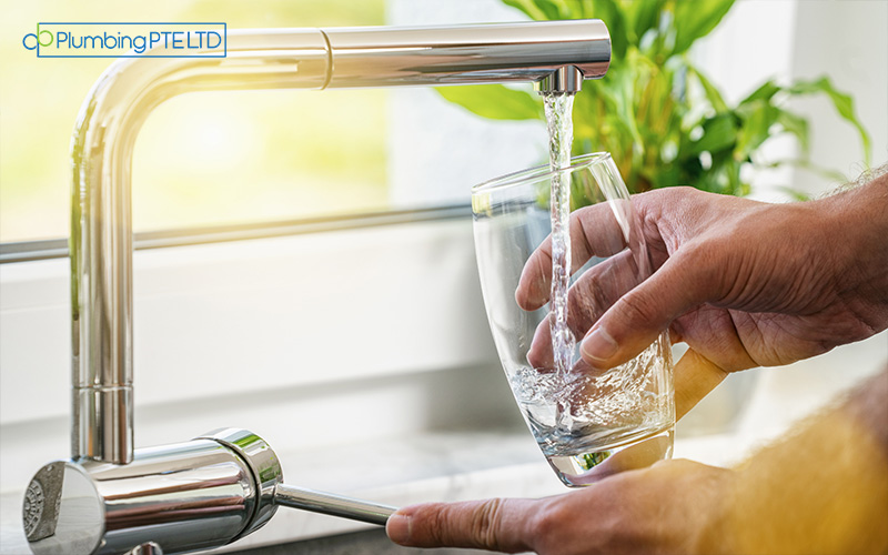A person holding a glass under a faucet, filling it with water.