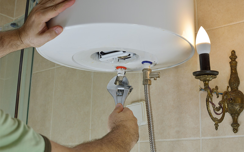 Person repairing water heater pipe connection.