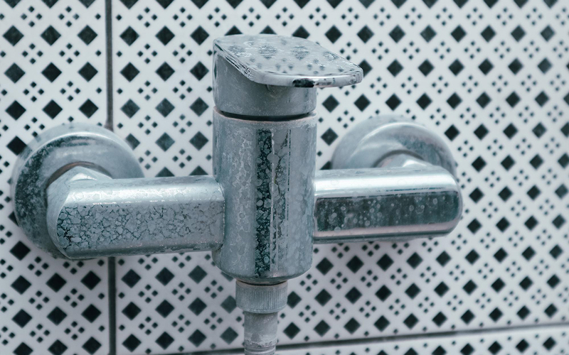 Heavy lime deposits visible on a chrome bathroom faucet.