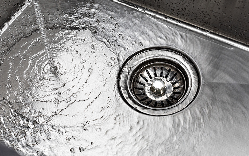Water running into a clean stainless steel kitchen sink.