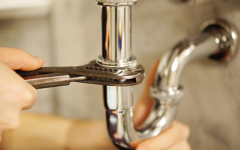 Plumber using a wrench to repair damaged bathroom pipes.
