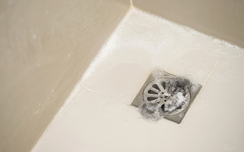 Clogged bathroom floor drain filled with hair and soap.