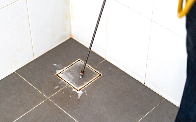 Professional treating a bathroom floor trap drain.