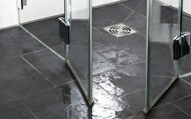 Clean glass shower stall and tiled floor trap.