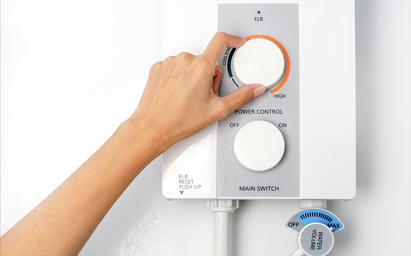 Hand adjusting dials on instant water heater.
