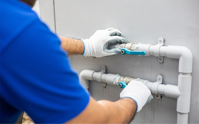 Person adjusting PVC pipes with valves.