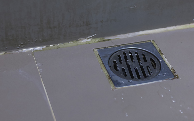Close-up of a wet balcony floor drain grid.