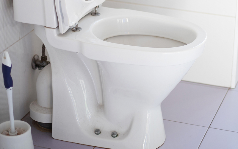 White ceramic toilet bowl base requiring repair before leaking.
