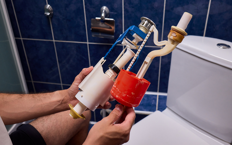 Plumber holding toilet flush valve assembly for repair service